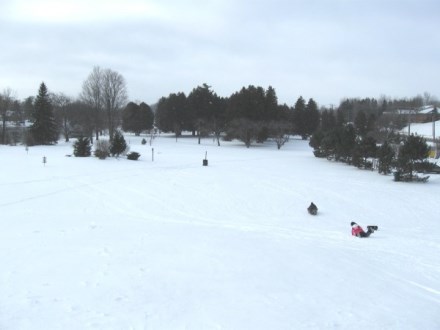 snowy toboggan hill at the disc golf park with a a toboggan rider