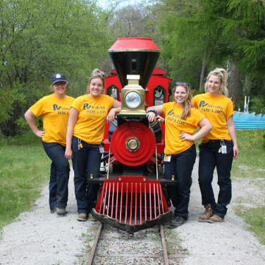 four employees posing with a mini train